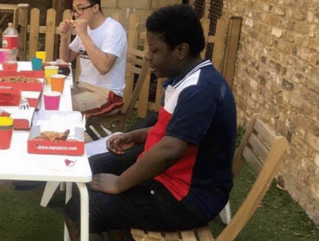 a man sitting at a table with a box of pizza on it that says ' www.mypizza.com '