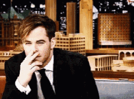 a man in a suit and tie is covering his nose with his hand .