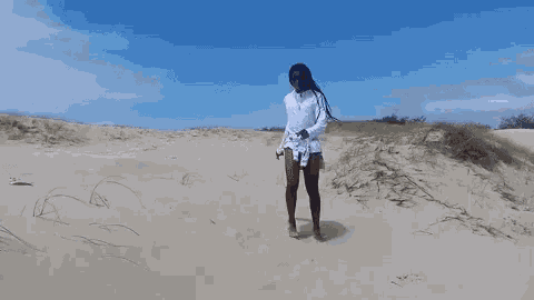 a woman in a white dress is dancing in the sand on a beach .