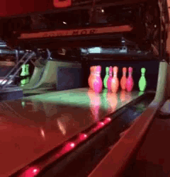 a bowling alley with glow in the dark bowling pins and a sign that says mos