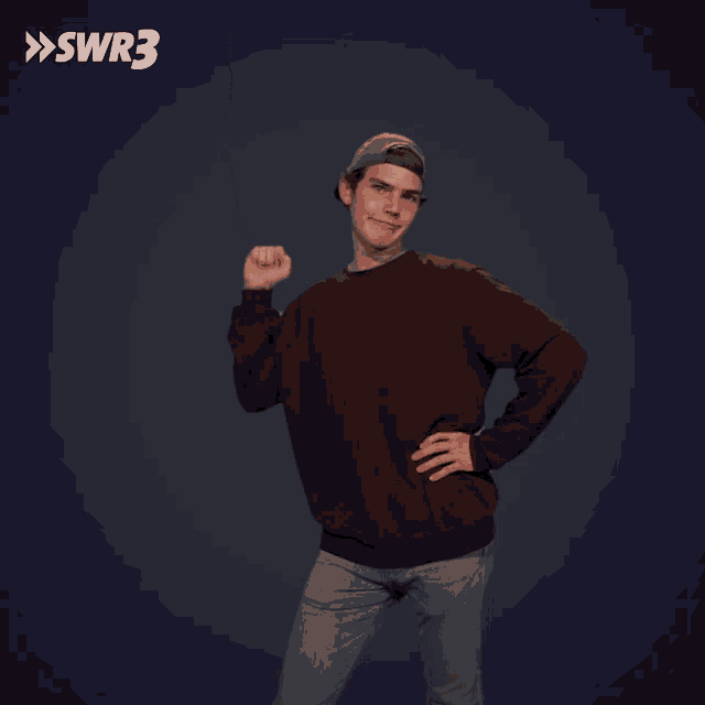 a man wearing a hat and a maroon sweater holds his fist in the air