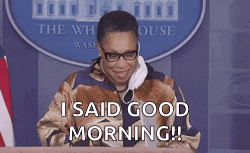 a woman wearing glasses and a face mask is sitting at a podium and saying i said good morning .