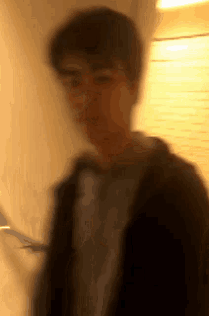 a blurry picture of a man wearing glasses and a jacket .