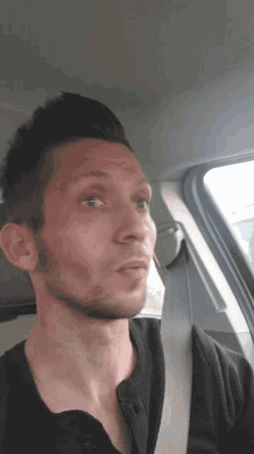 a man wearing a seat belt is looking out the window