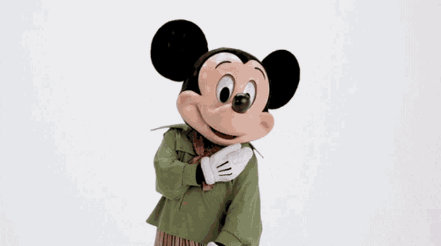 a mickey mouse mascot is wearing a green jacket and white gloves