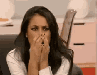 a woman is covering her face with her hands while sitting on a couch .