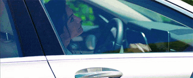 a man is sitting in a white car talking on a cell phone