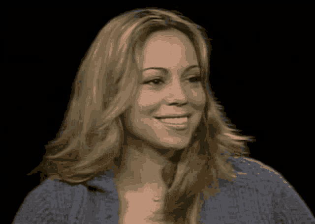 a woman with blonde hair and a blue sweater smiles