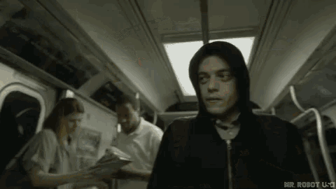 a man in a hoodie is riding a subway train .