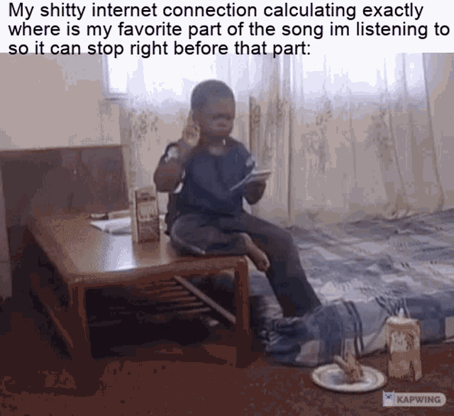 a young boy is sitting on a small table with a cell phone in his hand .