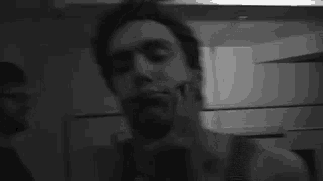 a man is taking a selfie in a black and white photo with his hand on his face .