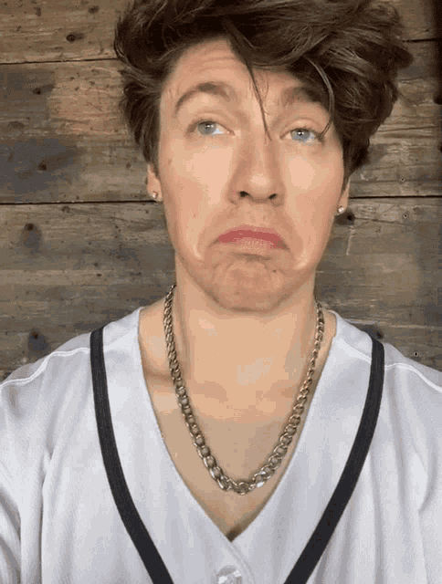 a man wearing a chain around his neck makes a face