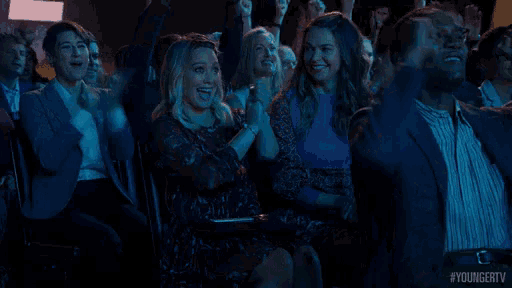 a group of people are sitting in a theater watching a show and laughing .