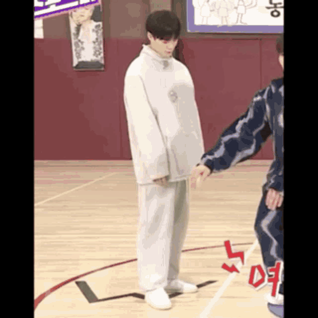 a man is standing on a basketball court holding another man 's arm .