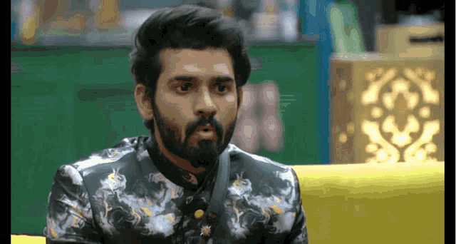 a man with a beard is sitting on a yellow couch and looking at something