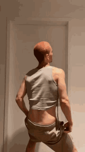 a man with red hair is standing in front of a door wearing a crop top and shorts