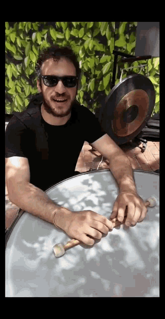 a man wearing sunglasses playing a drum