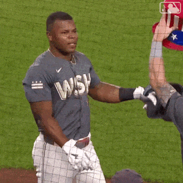 a baseball player wearing a shirt that says wsh is being helped up by another player