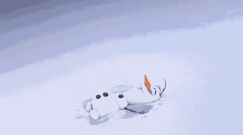 a snowman is laying on its back in the snow with a carrot in its mouth .