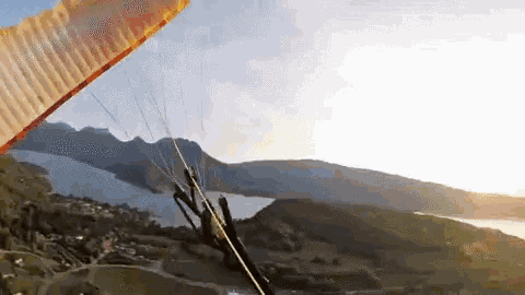 a person is flying a parachute over a valley with mountains in the background