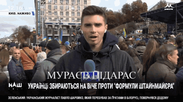 a man stands in front of a crowd with a microphone in his hand and says " muracb iidarac "