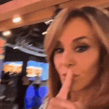 a woman is making a shhh gesture with her finger to her mouth .