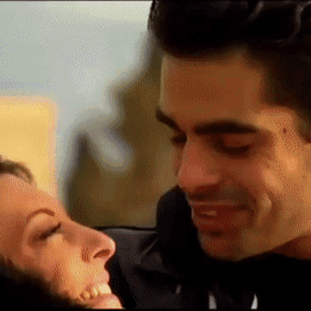 a man and a woman are looking into each other 's eyes and smiling
