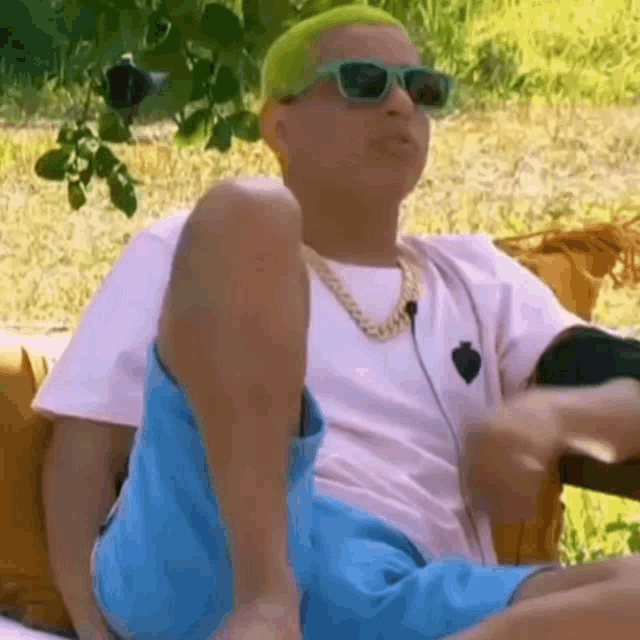 a man with green hair is sitting on a couch .