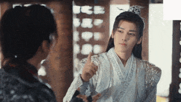 a man in a white kimono is giving a thumbs up to another man