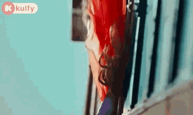 a woman with red hair is standing in front of a window .