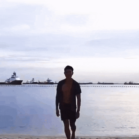 a man without a shirt is walking on a beach near the water .