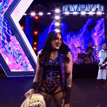 a woman is holding a trophy on a stage with a band behind her