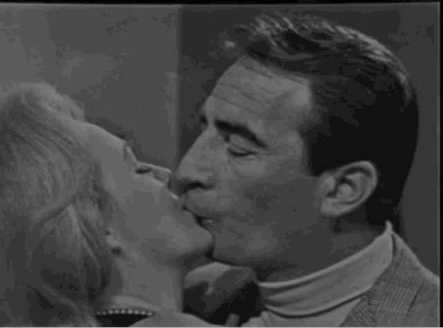 a black and white photo of a man and a woman kissing