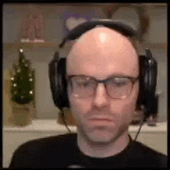 a bald man wearing headphones and glasses .