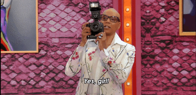 a man is holding a camera and saying yes girl .