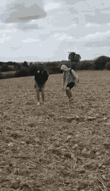 two people standing in a field with a cloudy sky
