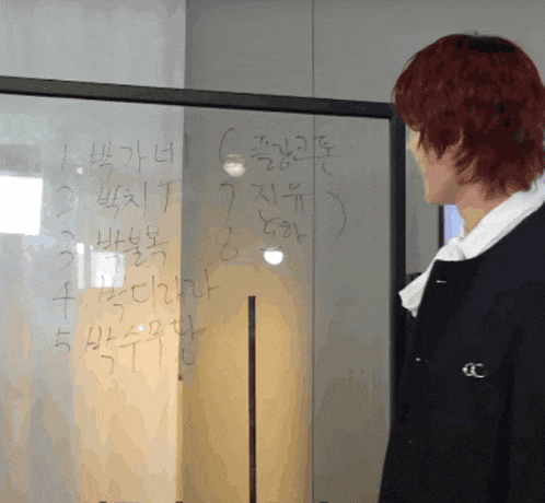 a man with red hair is looking at a white board with korean writing on it
