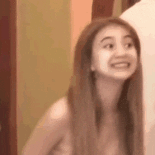 a woman without a shirt is smiling in a blurry photo .