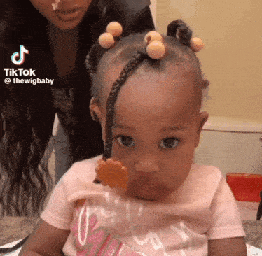 a little girl with braids and a flower in her hair is being held by a woman .