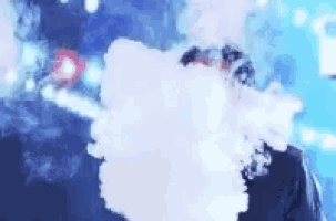 a man is smoking an electronic cigarette and making a cloud of smoke coming out of his mouth .