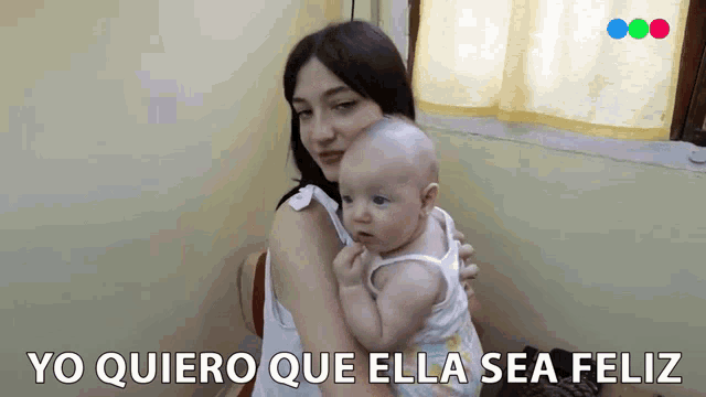 a woman holding a baby with the words yo quiero que ella sea feliz written below her