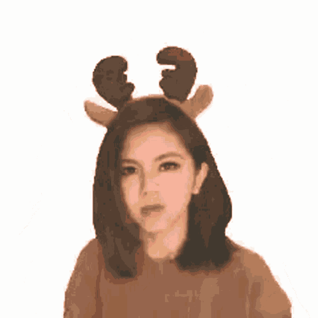 a woman wearing a reindeer headband with antlers is standing in front of a flaming background .