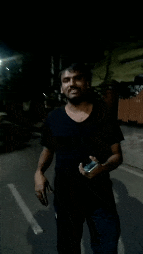 a man in a black shirt is walking down a street
