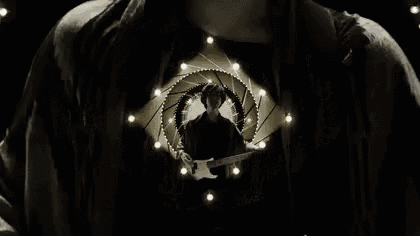 a man is playing a guitar in front of a circle of lights in a black and white photo .