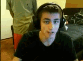 a young man wearing headphones is sitting in front of a computer screen .