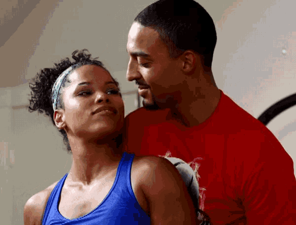 a man in a red shirt and a woman in a blue tank top are looking at each other