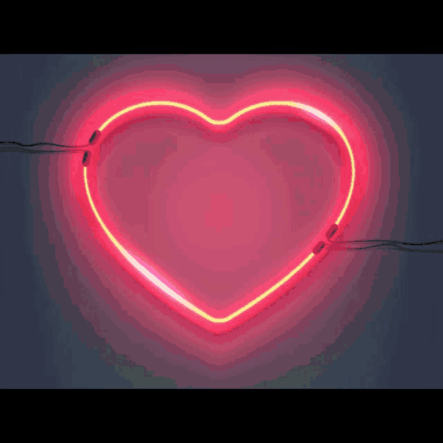 a blue heart shaped neon sign is glowing on a green background
