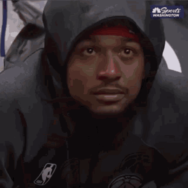 a man wearing a hoodie and a basketball jersey is sitting in a chair .