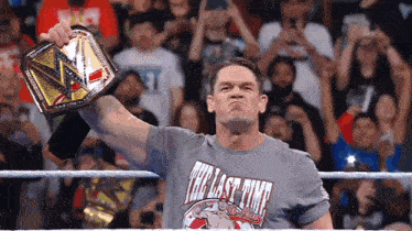 a wrestler wearing a shirt that says the last time is holding a championship belt