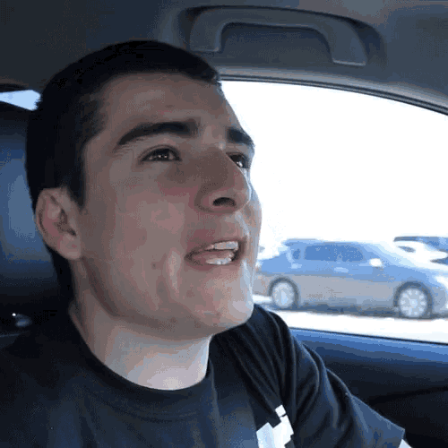 a young man is sitting in the back seat of a car making a funny face